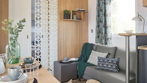 Una sala de estar moderna con un sofá, una mesa de centro, una planta decorativa y un ventanal con cortinas.