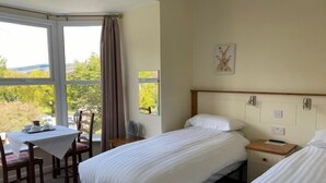 A hotel room with two beds, a dining table, and a view of the outdoors. - Church hill house (Betws-Y-Coed)