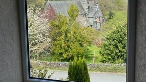A window with a view of a stone building surrounded by trees. - Church hill house (Betws-Y-Coed)