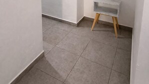 A room with a tiled floor, a white wall, and a small table with a marble-like top. - Private Apartment, Milan Providencia (Guadalajara)