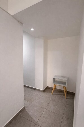 Ein Zimmer mit Fliesenboden, einer weißen Wand und einem kleinen Tisch mit einer marmorähnlichen Oberfläche.
