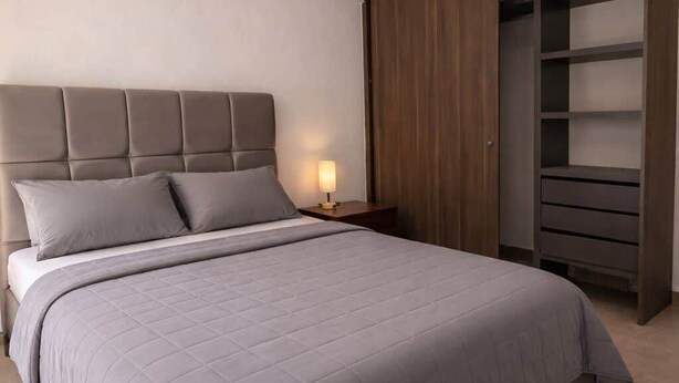 A bedroom with a large bed, a nightstand, a bedside lamp, and a wardrobe. - Private Apartment, Milan Providencia (Guadalajara)