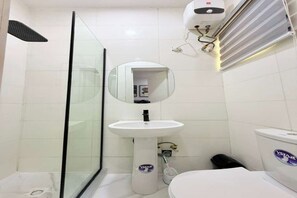 A bathroom with a glass shower enclosure, a pedestal sink, a toilet, and a hand dryer. - UV Residence | 2BR Duplex (Lekki)