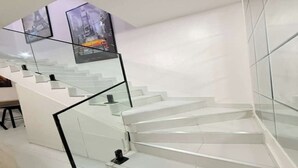 Een moderne trap met glazen leuning en witte wanden.