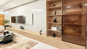 Een moderne woonkamer met een grote flatscreen televisie, een houten boekenkast, een salontafel en een bank.