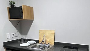 Eine kompakte Küche mit Spüle, zwei Geschirrspülern, integriertem Herd und Holzschränken.