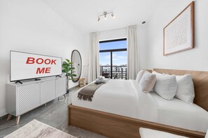 A modern hotel room with a large bed, a TV, a view of the city, and a balcony. - Free Housekeeping Visits During Your Stay - Stayshort - Relaxing Studio in Arjan That Sleeps 3 (Dubai)