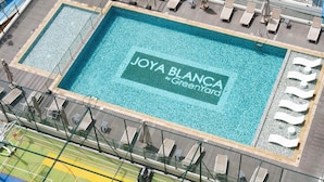 Uima-allas, jonka yhteydessä on kyltti, jossa lukee ”JOYA BLANCA #GreenYard”, ja sen vieressä sijaitseva koripallokenttä.