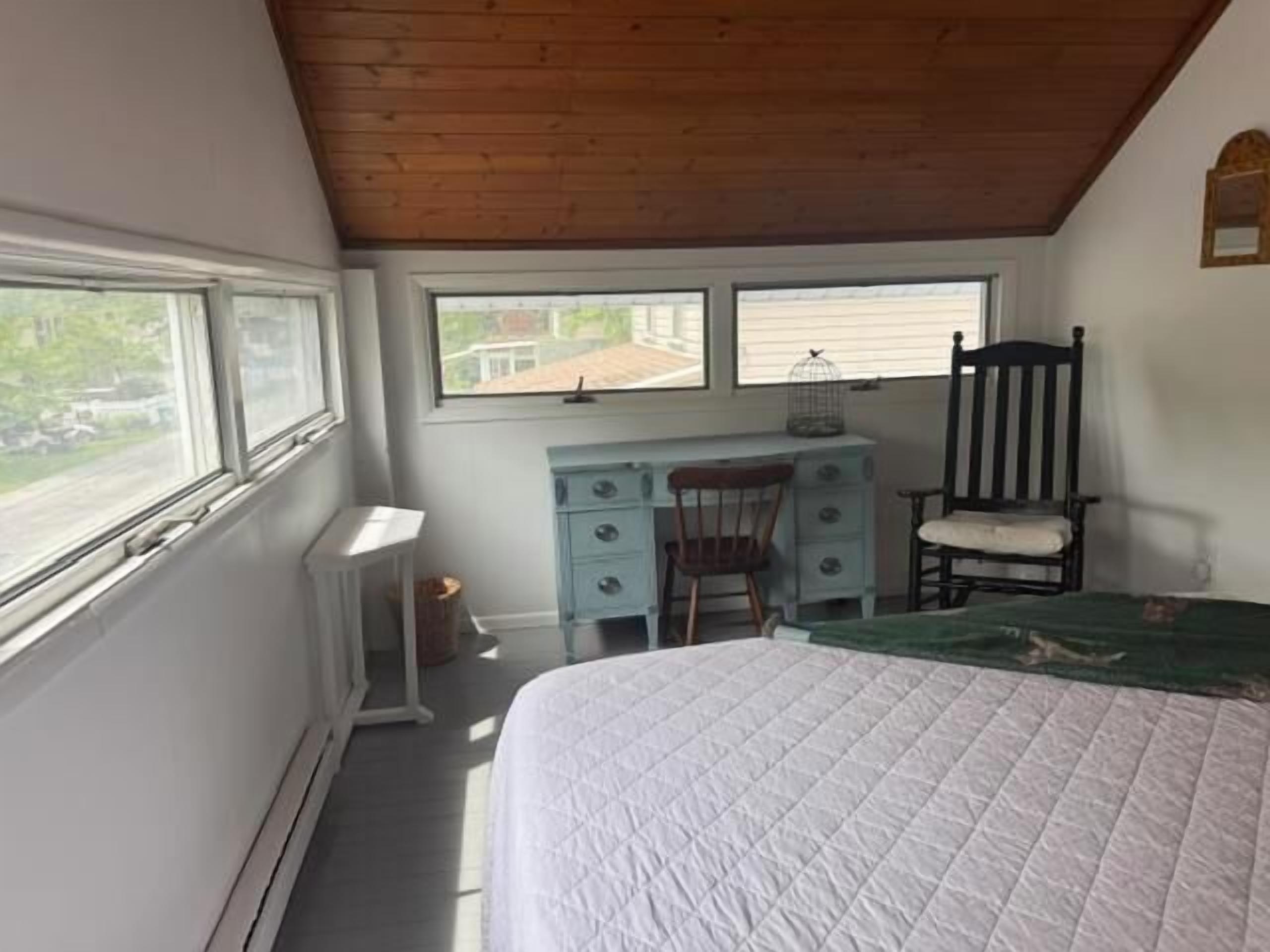 Um quarto com uma cama, uma escrivaninha, uma cadeira e uma janela.