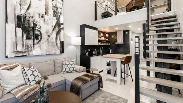 Un espacio habitable moderno estilo loft con cocina, comedor y escalera.