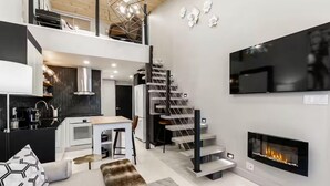 Un interior moderno con cocina, comedor, escalera y chimenea.
