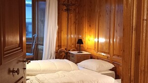 Une chambre à coucher aux murs lambrissés, avec un lit, des tables de chevet et une lampe.