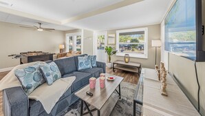 A living room with a sofa, coffee table, and foosball table. - Cozy 3BR Clearwater Home w/ Private Pool & Backyard Oasis (Clearwater)