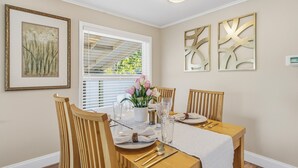 A dining room with a table set for four, a window with blinds, and two wall-mounted abstract art pieces. - Cozy 3BR Clearwater Home w/ Private Pool & Backyard Oasis (Clearwater)