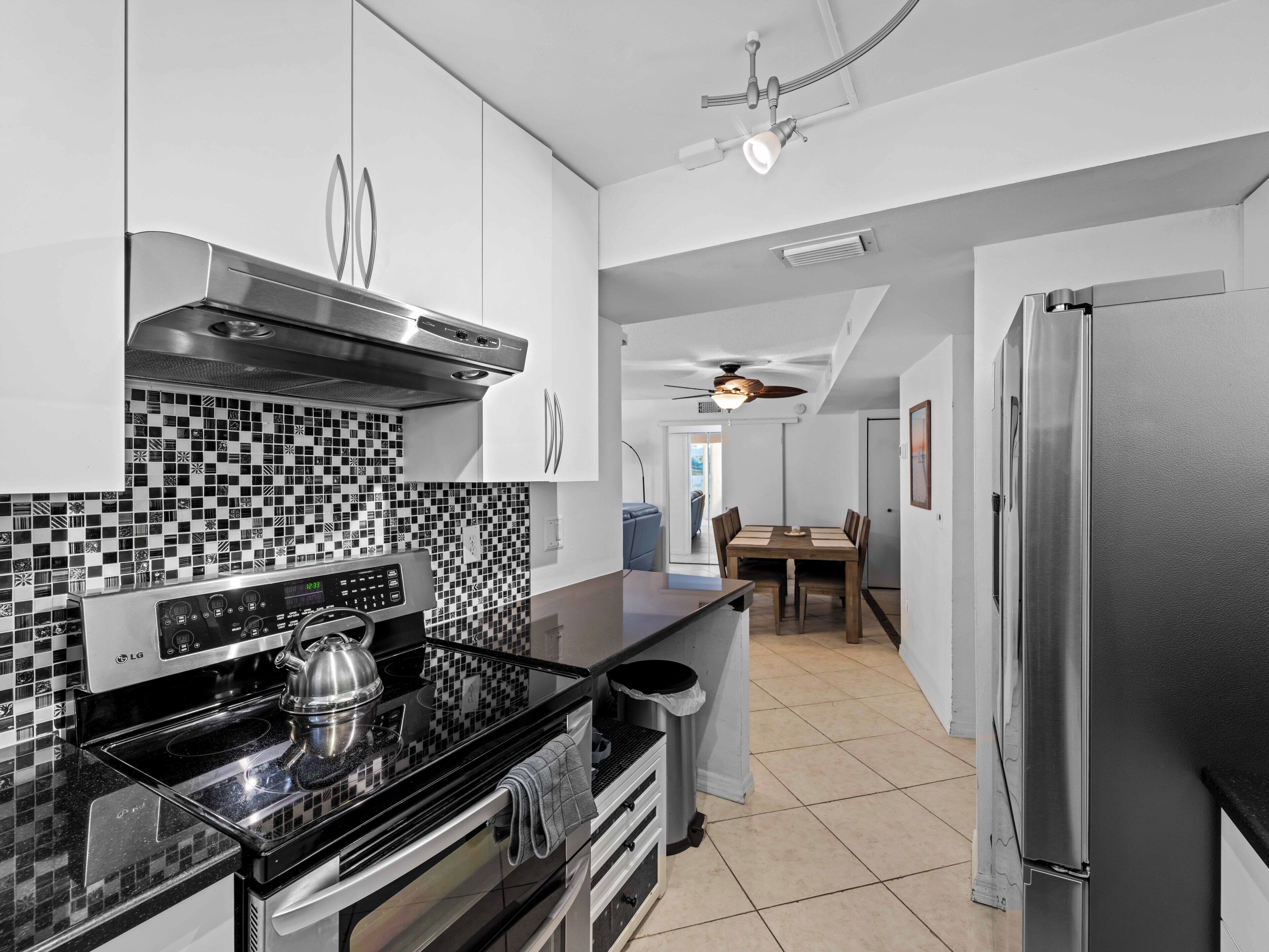 A modern kitchen with a black and white tiled backsplash, stainless steel appliances, and a dining area with a table and chairs.