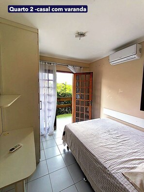 A bedroom with a bed, a wardrobe, a window with curtains, and an air conditioning unit.