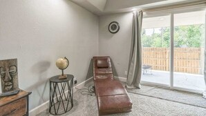 Quarto com mesa de massagem, um globo em uma mesinha lateral e uma janela grande com vista para uma cerca de madeira.