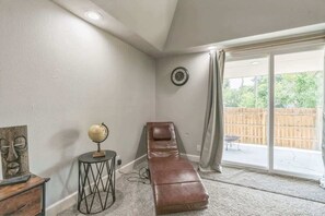 A room with a massage table, a globe on a side table, and a large window with a view of a wooden fence.