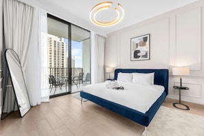 A modern hotel room with a large bed, a balcony with outdoor furniture, and a city view. - Free Housekeeping Visits During Your Stay - Stayshort - Elegant 1 Bedroom in JVC Sleeps 4 With Balcony (Dubai)