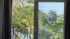 Ein Zimmer mit einer Schiebeglastür und Blick auf Bäume sowie ein Gewässer.