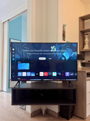 A flat-screen TV on a stand with a Smart Hub interface displaying various streaming apps. - Cozy 1-bedroom apartment in beautiful Glifada with AC (Glifada)