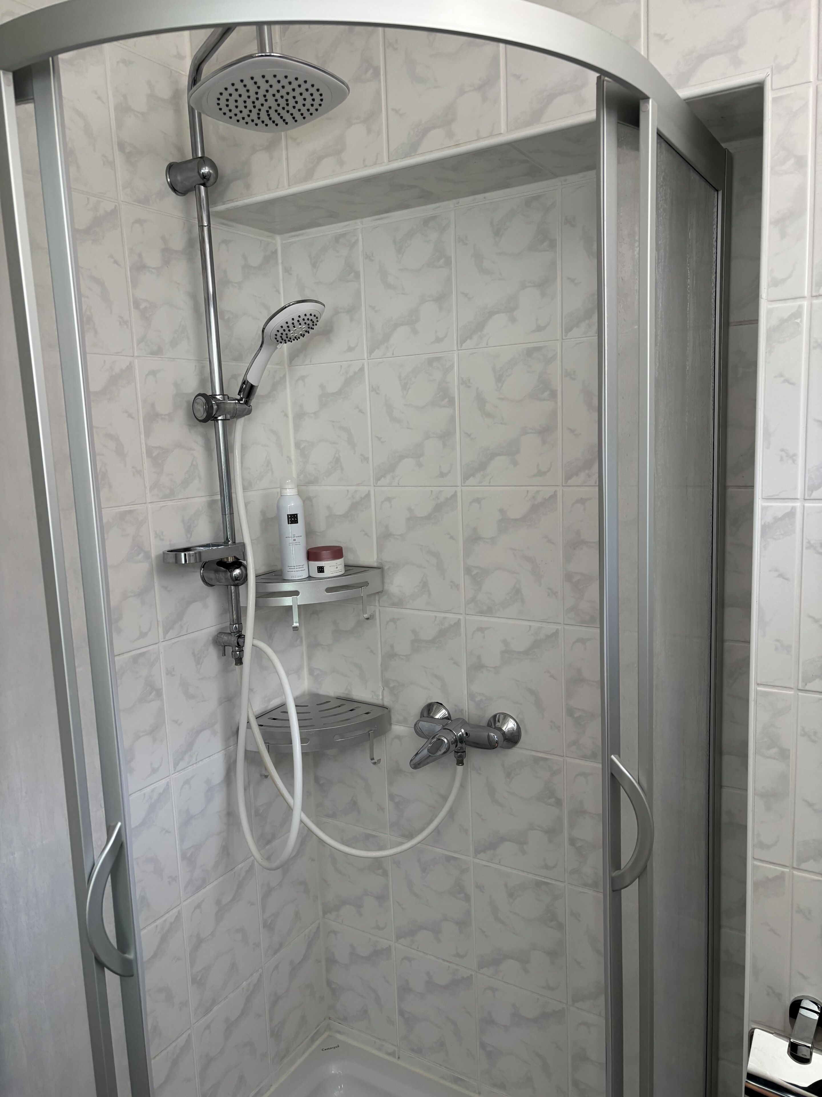 Une douche équipée d’un pommeau de douche à main, d’un pommeau de douche fixé au mur et d’un robinet à main.