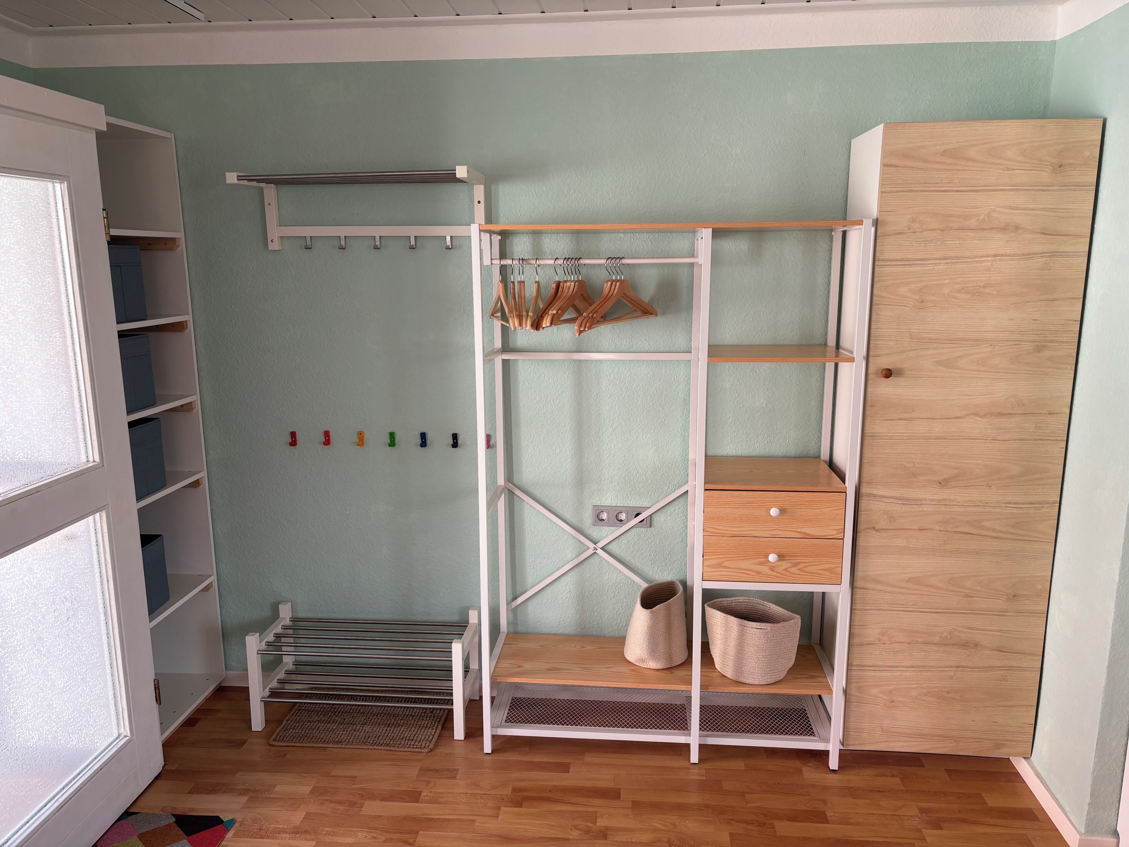 Une pièce comprenant une armoire en bois, une étagère blanche avec des crochets et un petit banc.