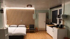 A compact room with a bed, a small table, a chair, a kitchenette, and a door. - Studio with kitchen in the center of Auerbach near Fürstenlager (Bensheim)