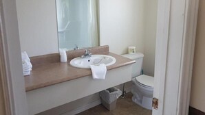 Ein Badezimmer mit Waschbecken, Spiegel, Toilette und Mülleimer.