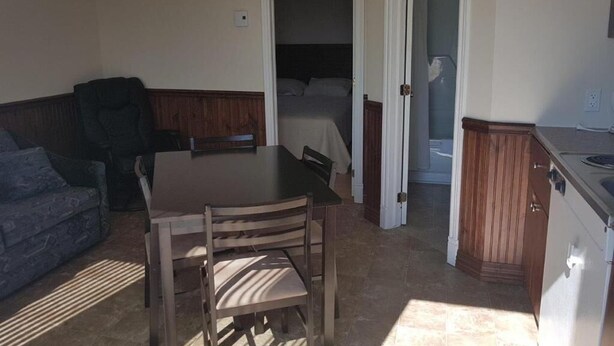 Ein Zimmer mit Esstisch, Stühlen, einer Couch, einem Bett und einer Küchenzeile.