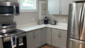 A modern kitchen with stainless steel appliances, grey cabinets, and a wooden floor. - Stylish 3BR Apt in Savannah’s  Perfect for  Nurses, students  & Professionals! (Savannah)