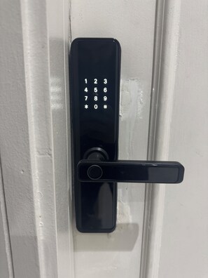 A modern door lock with a numeric keypad and a lever handle. - Self Checkin Studio - Olaya 203 (Riyadh)