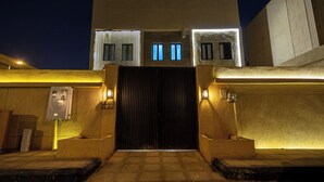A building entrance with a gated driveway, a lighted wall, and a utility box. - Self Checkin Studio - Olaya 203 (Riyadh)
