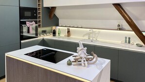 Et moderne køkken med en central ø, indbyggede hårde hvidevarer og et træloft.