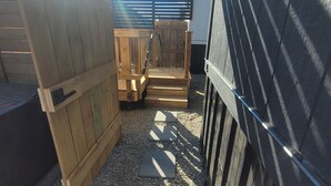 A wooden deck with a metal gate, gravel pathway, and a wooden fence.