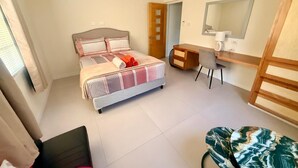 A bedroom with a bed, desk, chair, and a ceiling fan. - 1BR NEWLY REFURBISHED Apartment | Pool | Minutes to Oistins (Oistins)