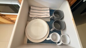 A drawer with a white plate, a striped napkin, and several white mugs. - 1BR NEWLY REFURBISHED Apartment | Pool | Minutes to Oistins (Oistins)