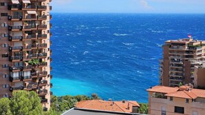 Un edificio alto con balconi affacciato su un mare cristallino e blu.