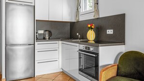 Una cucina compatta con frigorifero, forno e macchina del caffè.
