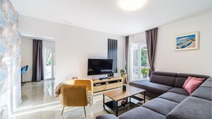 A modern living room with a sofa, a TV, a coffee table, and a plant.