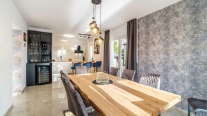 A modern dining area with a wooden table, black chairs, and pendant lighting.