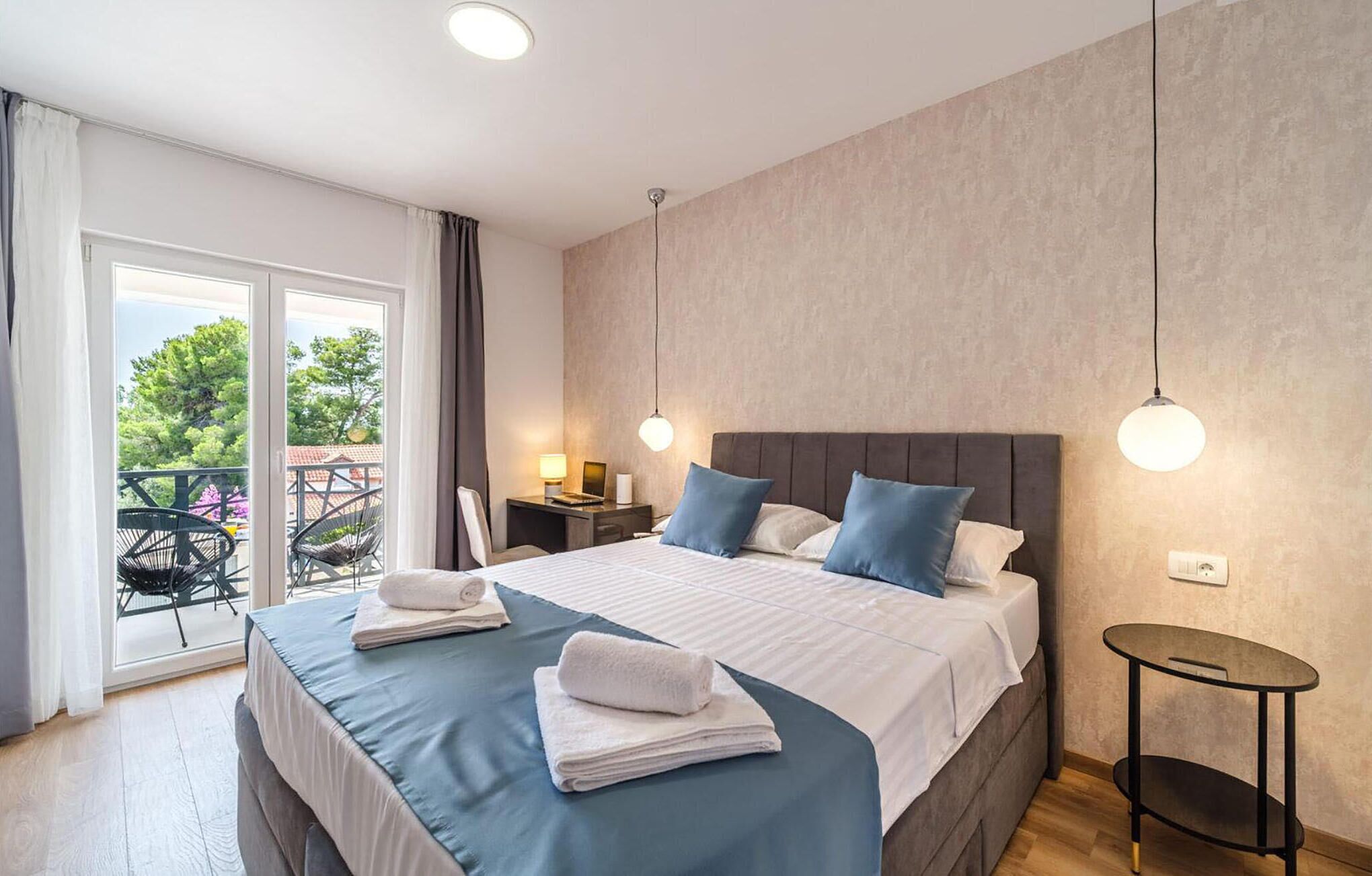Une chambre d’hôtel avec un grand lit, une petite table de chevet, une chaise et une vue sur l’extérieur.