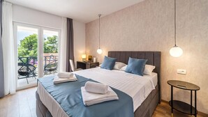 A hotel room with a large bed, a small bedside table, a chair, and a view of the outdoors.
