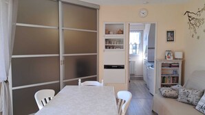 Un espacio habitable compacto con una mesa de comedor, un sofá, una zona de cocina y una puerta corredera.