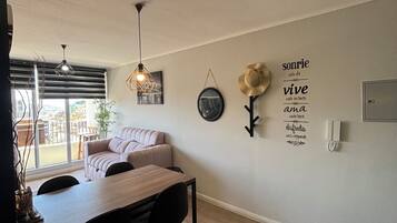 A modern dining area with a wooden table and chairs, a sofa, and a wall-mounted light fixture.
