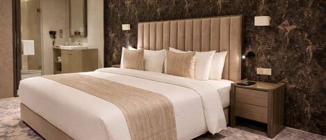 A bedroom with a large bed, a nightstand, a mirror, and a bathroom visible through an open door.