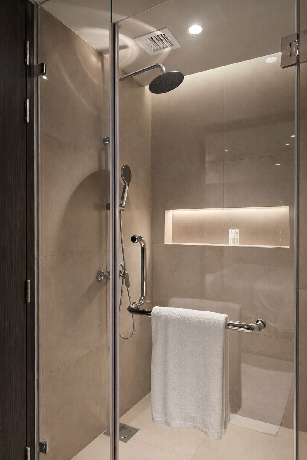 A modern shower with a handheld showerhead, a handheld showerhead, and a glass-enclosed shower stall.