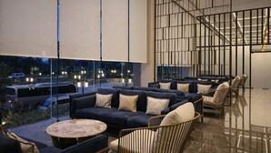 A modern lounge area with sofas, chairs, and a glass wall offering a view of the cityscape. - colombo international airport hotel (Katunayake)