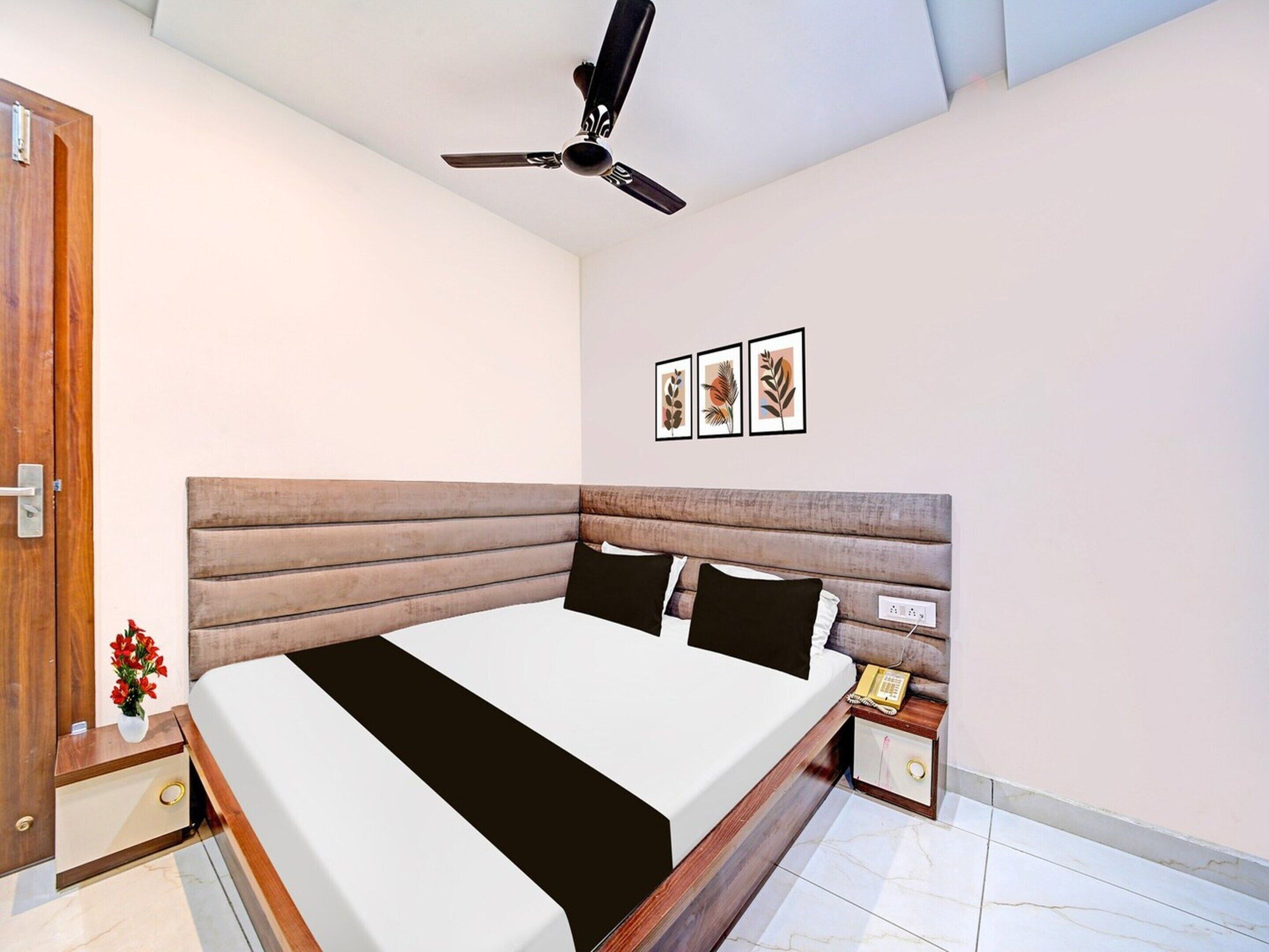 A bedroom with a bed, wooden headboard, bedside table, nightstand, and a ceiling fan.