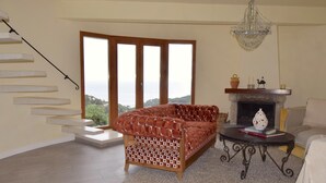 Ein Wohnzimmer mit einer Couch, einem Kamin, einer Chandelieber und einer Treppe.
